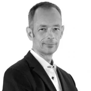 Black and white professional headshot of a man in a dark blazer
